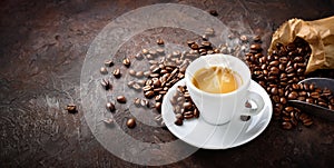 Espresso cup and roasted coffee beans on plaster background, space for text.