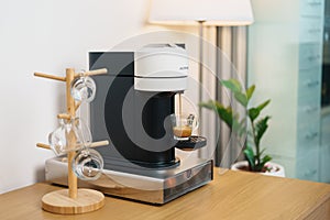 Espresso cup with steam and froth during Coffee making Coffee by Coffee Maker Machine on wood table bar. Cafe shop, Daily beverage