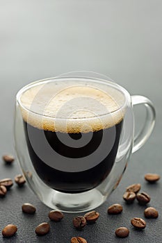 espresso on glass cup and coffee beans on grey table