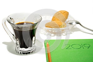 Espresso with green notebook on a white background.