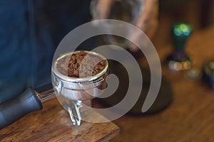 Espresso handle filled with ground coffee. Barista prepares espresso in his coffee shop