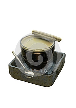Espresso with milk foam served with Crispy Stick Candy on a Transparent Glass and Brass Spoon on Ceramic Saucer isolated on white
