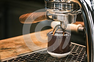 Espresso pouring from coffee machine. coffee machine preparing fresh coffee and pouring into red cups at restaurant, bar or pub