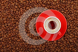 Espresso in red cup with saucer on coffee beans