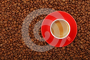 Espresso in red cup with saucer on coffee beans
