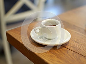 Espresso in white cup on wooden table in cafe