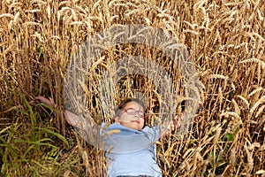 Essence of the peaceful and joyful moment of a little girl with glasses lying in a beautiful wheat field, enjoying the serenity