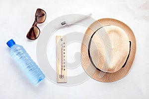 Essential accessories for summer heat: sunglasses, hat, sunscreen, bottle of water. Flat lay, top view