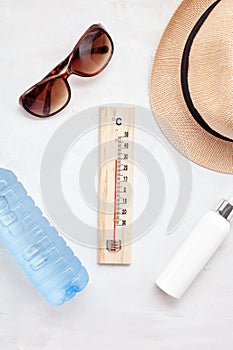 Essential accessories for summer heat: sunglasses, hat, sunscreen, bottle of water. Flat lay, top view