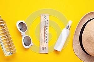 Essential accessories for summer heat: sunglasses, hat, sunscreen, bottle of water. Flat lay, top view