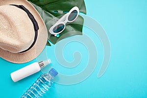 Essential accessories for summer heat: sunglasses, hat, sunscreen, bottle of water. Flat lay, top view