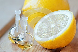 Essential aroma oil in glass bottle with fresh, juicy lemon fruit on wooden background. Beauty treatment. Spa concept. Selective f