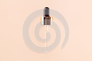 Essential clear oil or serum in pipette isolated on beige background close up. cosmetic pipette