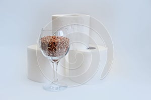 Essential goods for a coronovirus pandemic. rice and buckwheat are in a wine glass instead of wine and toilet paper rolls