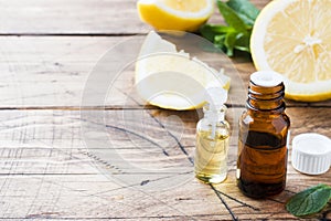 Essential lemon oil in bottle, fresh fruit slices on wooden background. Natural fragrances