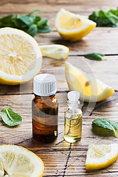 Essential lemon oil in bottle, fresh fruit slices on wooden background. Natural fragrances