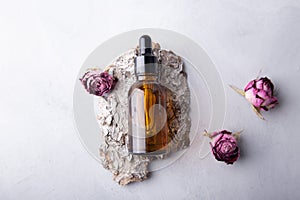 Essential oil bottle with dried roses on bark minimalist natural skincare presentation