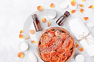 Essential oil bottle, rose flower in bowl, towel and candles on stone table top view. Spa, aromatherapy, wellness, beauty.