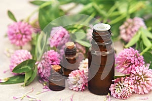 Essential oil bottles on clover flowers and herbs background