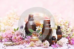 Essential oil bottles on medicinal pink flowers and herbs background