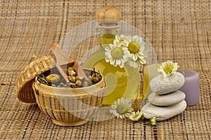 Essential oil, Chamomile Flowers and oil on a brown hemp sack background.