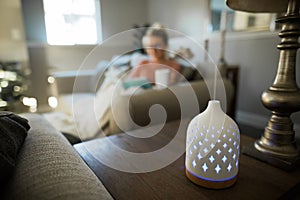 Essential oil diffuser with a young woman relaxing in the background