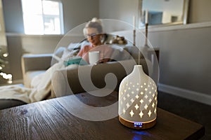 Essential oil diffuser with a young woman relaxing in the background photo