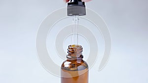 Essential oil dropping from pipette to bottle. Essence liquid cosmetic. Dropper glass bottle with liquid cosmetic serum