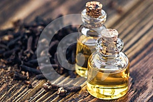 Essential oil in glass bottle and dry cloves on dark wooden background copy space beauty treatment. Fragrant oil of cloves, macro,