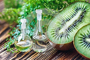 Essential oil in glass bottle with fresh, juicy kiwi fruit and green leaves-beauty treatment. Spa concept. Selective focus.