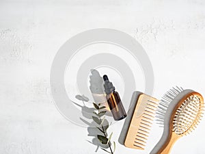 Essential oil for hair care with wooden hair comb and bamboo comb on white background