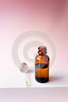 Essential oil serum glass pipette and bottle on pink background. Natural Serums. Cosmetic concept photo