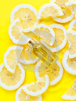 Essential oil, serum on textured background with yellow lemon slice