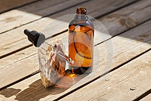 Essential oil for skin care in a brown glass bottle with a pipette on a wooden background