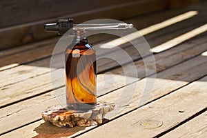 Essential oil for skin care in a brown glass bottle with a pipette on a wooden background