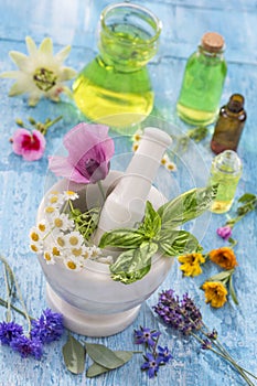 Essential oils for aromatherapy treatment with fresh herbs in mortar white background