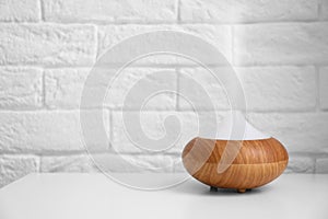 Essential oils diffuser on white table   near  wall. Space for text