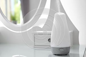 Essential oils diffuser on white table. Space for text