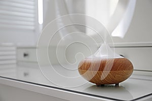 Essential oils diffuser on white table . Space for text