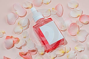 Essential oils with drops pipette on pink background. Scattered rose petals. Professional bottle for facial and body treatment