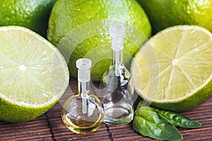 Essential oils in glass bottle with fresh, juicy, ripe limes. Beauty treatment. Spa concept. Selective focus. Small bottles of per