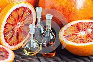 Essential oils in glass bottle with fresh, juicy, ripe, red orange. Beauty treatment. Spa concept. Selective focus.