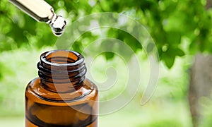 Essential oils with water drops in to the bottle on green bokeh background