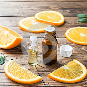 Essential orange oil in bottle, fresh fruit slices on wooden background. Natural fragrances