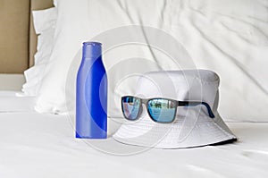 essentials for sun protection: sun lotion, sunglasses, hat. hat, sunglasses and UV cream on bed