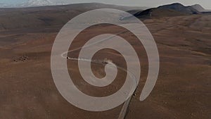 Establishing shot aerial view car driving gravel trail path in Icelandic dusty desert. Drone view 4x4 vehicle speeding