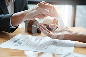 estate agent giving house keys to man and sign agreement in office