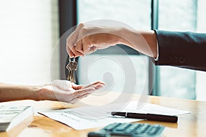 estate agent giving house keys to man and sign agreement in office with vintage filter