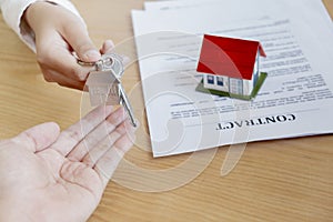 Estate agent giving house keys to owner and sign agreement in office