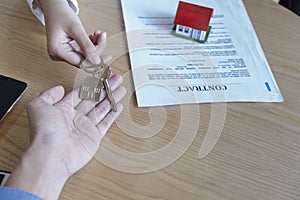 Estate agent giving house keys to owner and sign agreement in office